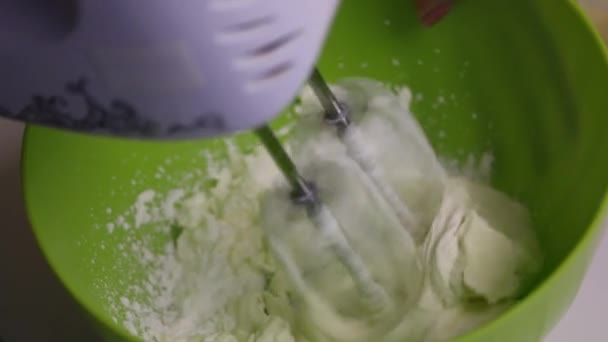 Mujer bate crema para pastel. En un recipiente de plástico con una batidora . — Vídeo de stock