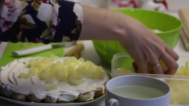 Žena dělá dort ze savoiardských sušenek. Dává ananas na smetanu. Poblíž ananasu a smetany. — Stock video