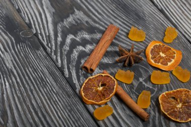 Jöle çiğneyen şekerler. Kurutulmuş portakal dilimleri, tarçın çubukları ve anason yıldızları. Fırçalanmış çam ağaçlarının üzerine siyah beyaz boyanmış..