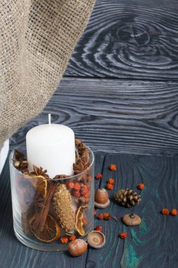 Cam bir kapta büyük bir mum. Koniler, dağ külleri, anason yıldızları, tarçın çubukları dekorasyon için içine dökülüyor. Dişlerimi fırçaladı.