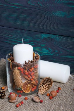 Cam bir kapta büyük bir mum. Koniler, dağ külleri, anason yıldızları, tarçın çubukları dekorasyon için içine dökülüyor. Meşe palamutları, Rowan çilekleri yakınlarda ve bir mum uzanıyor. Köstebeğe karşı