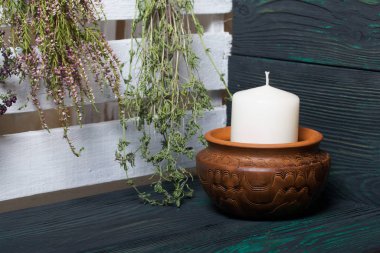 Cam bir kapta büyük bir mum. Koniler, dağ külleri, anason yıldızları, tarçın çubukları dekorasyon için içine dökülüyor. Siyah ve yeşile boyanmış tahtaların üzerinde duruyor..