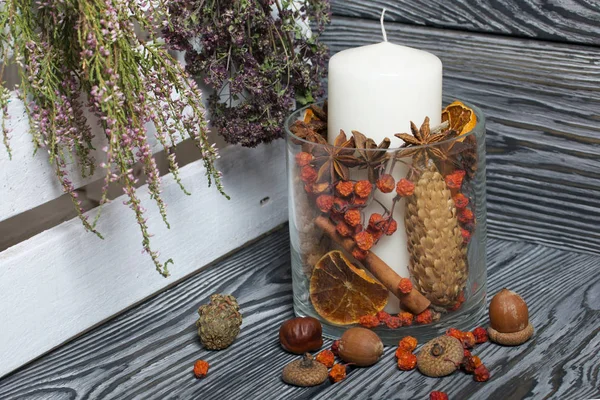 Cam bir kapta büyük bir mum. Koniler, dağ külleri, anason yıldızları, tarçın çubukları dekorasyon için içine dökülüyor. Palamutlar, dağ külleri ve güzel kokulu çimenler etrafa saçıldı. Ayağa kalk.