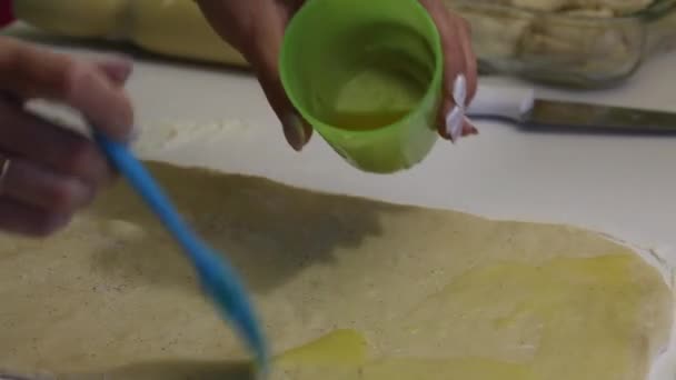 Egy nő zsíros tésztát sodort ghee-s fahéjasoknak. Az asztal liszttel van megszórva.. — Stock videók