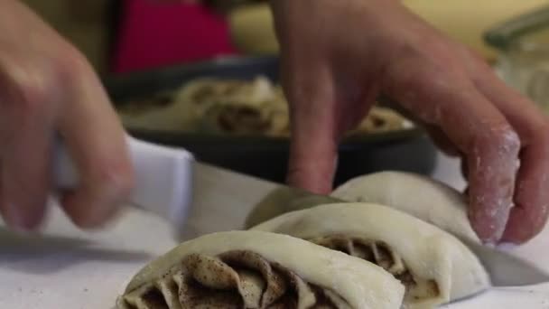 Een vrouw zet op een bakplaat deeg stukken voor cinnabon. Close-up opname. — Stockvideo