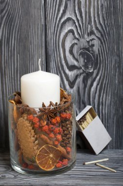 Cam bir vazoda baharatlı mum. Fırçalanmış tahtaların arka planına karşı.