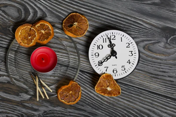 Svíčka na kartáčovaných prknech. Blízko hodin, zápalky a sušené pomeranče. — Stock fotografie