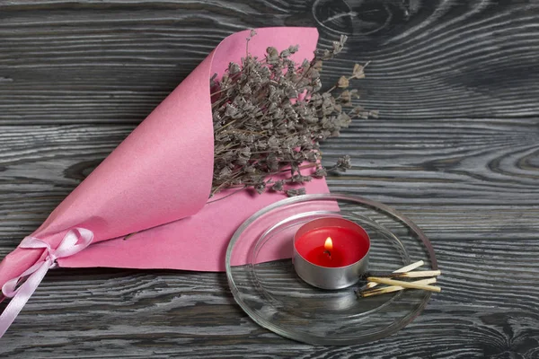 Kaars branden op geborstelde planken. In de buurt is een boeket van lavendel en verbrande lucifers. — Stockfoto