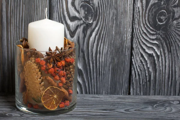 Cam bir vazoda baharatlı mum. Fırçalanmış tahtaların arka planına karşı.