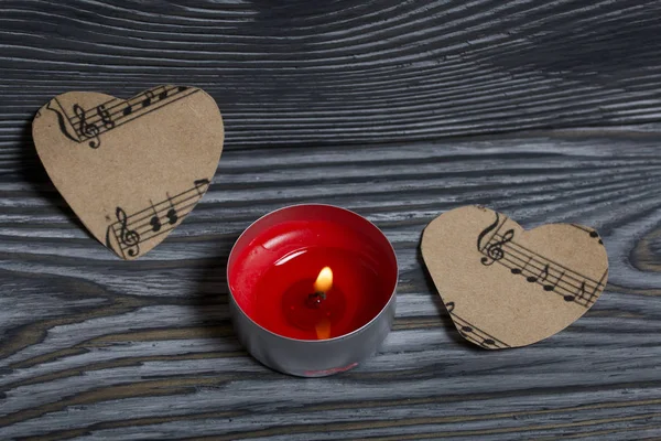 A burning candle and two hearts cut out of paper with notes. Against the background of brushed boards. — 스톡 사진