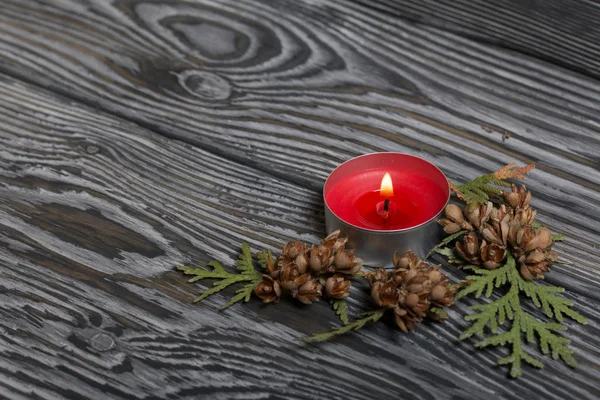 Burning candle on brushed boards. Near branches and cones of thuja. — 스톡 사진