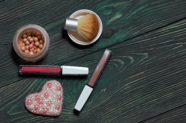 Boncuktan broş. Makyaj setinin yanında. Siyah ve yeşile boyanmış çam ağaçlarında.