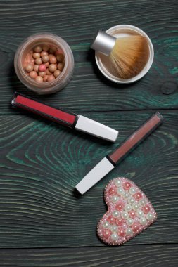 Boncuktan broş. Makyaj setinin yanında. Siyah ve yeşile boyanmış çam ağaçlarında.