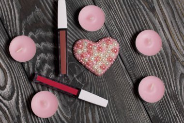 Boncuktan broş. Dekoratif mumların yanında ve makyaj seti. Siyah beyaza boyanmış çam ağacından tahtalara.