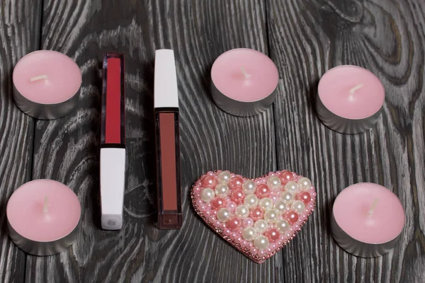 Boncuktan broş. Dekoratif mumların yanında ve makyaj seti. Siyah beyaza boyanmış çam ağacından tahtalara.