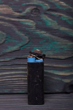 Aşınmayla kaplı kullanılmış piller. Siyah ve yeşile boyanmış çam ağaçlarının arka planında.