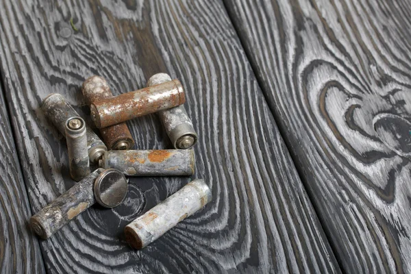 Baterias do tipo dedo usado revestidas com corrosão. Deitam-se em tábuas de pinheiro escovado pintadas a preto e branco . — Fotografia de Stock