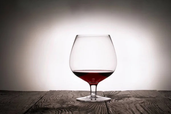 Um copo de vinho tinto seco. Fica em tábuas de madeira. Tiro na luz de fundo . — Fotografia de Stock