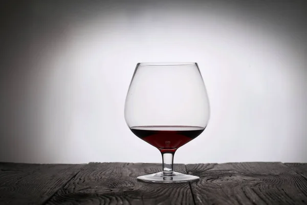Um copo de vinho tinto seco. Fica em tábuas de madeira. Tiro na luz de fundo . — Fotografia de Stock