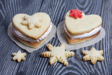 Kartanesi şeklinde kurabiyelerle süslenmiş marshmallow sandviçleri. Siyah beyaza boyanmış çam ağacından tahtalara.