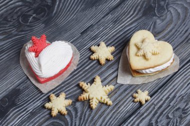 Kartanesi şeklinde kurabiyelerle süslenmiş marshmallow sandviçleri. Siyah beyaza boyanmış çam ağacından tahtalara.