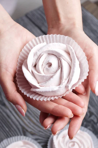 一个女人的手掌上长着玫瑰花状的棉花糖。 在黑白相间的画板的背景下. — 图库照片