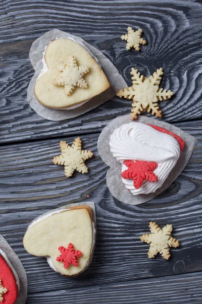 Marshmallow sandwiches decorated with cookies in the shape of a snowflake. On brushed pine boards painted in black and white.