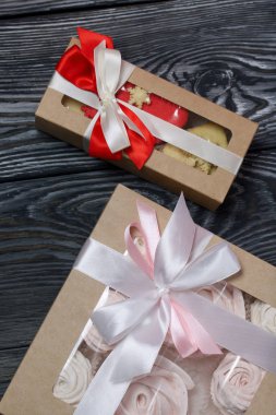 Kağıt ambalajda marşmelovlu sandviç. Fiyonka bağlanmış bir kurdeleyle bağlanmış. Siyah ve beyaza boyanmış çam ağaçlarında.