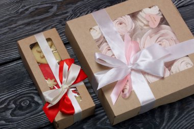 Kağıt ambalajda marşmelovlu sandviç. Fiyonka bağlanmış bir kurdeleyle bağlanmış. Siyah ve beyaza boyanmış çam ağaçlarında.