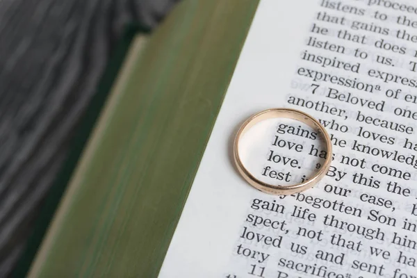 De verlovingsring ligt op de pagina van een open Bijbel. In het midden van de ring staan twee woorden Liefde. — Stockfoto