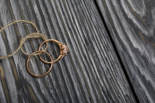 Wedding rings tied with a rope. On brushed pine boards painted in black and white.