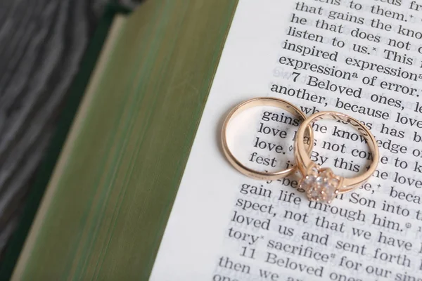 Trouwringen liggen op de pagina van een open Bijbel. In het midden van de ring staan twee woorden Liefde. — Stockfoto