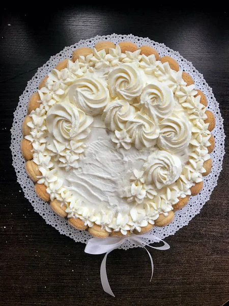 Bolo de esponja com creme de queijo, decorado com biscoitos Savoiardi. No lado, envolto em uma fita amarrada a um arco . — Fotografia de Stock