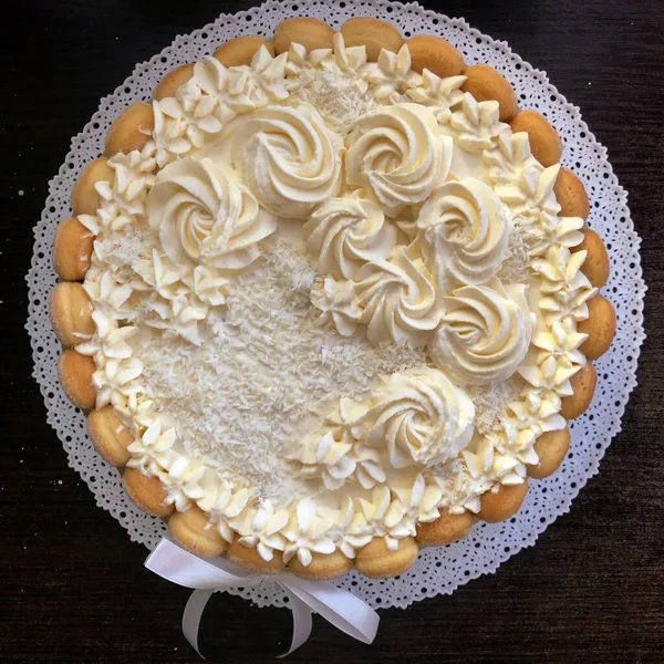 Pastel de esponja con queso crema, decorado con galletas Savoiardi. En el costado, envuelto en una cinta atada a un lazo . — Foto de Stock