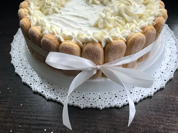 Sponge cake with cream cheese, decorated with Savoiardi cookies. On the side, wrapped in a ribbon tied to a bow. — Stock Photo, Image