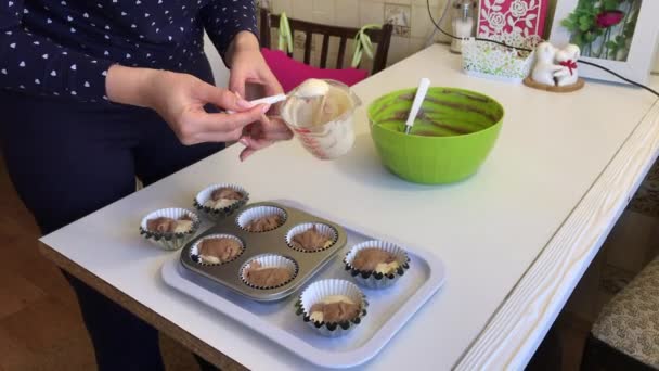 Frau legt Teig mit Kakao in Muffinform. die Formulare enthalten bereits ein wenig leichten Teig. — Stockvideo