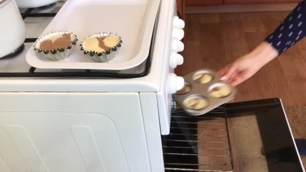 Женщина кладет в духовку формы с тестом для выпечки кексов. Делать мраморный торт . — стоковое видео