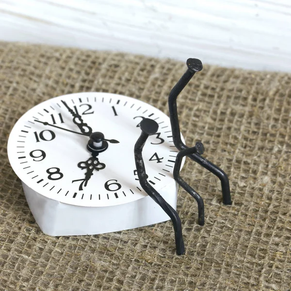 Figuras de hombre hechas de clavos de carpintería. Están sentados en el dial del reloj, uno al lado del otro. Entre ellos se encuentra una figura de un niño de un clavo. Símbolo del amor y el paso inexorable de ti —  Fotos de Stock