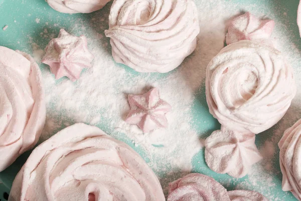 Zarte rosa Marshmallows in verschiedenen Formen. Liegt auf einem türkisfarbenen Tablett. Mit Puderzucker bestreut. — Stockfoto