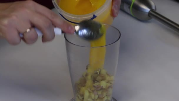 A man adds a spoon of honey to a blender bowl. In a bowl are sliced slices of ginger. For cooking ginger with honey — Stock Video