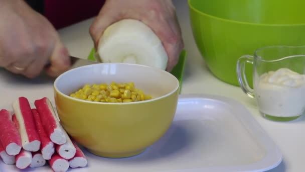 En man gör en sallad av Pekingkål. Skivor kål med en kniv på en skärbräda. Bredvid bordet finns andra ingredienser. Majs, krabbpinnar och majonnäs. Närbild. — Stockvideo