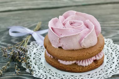 Çikolata hamuru ve yaban mersinli marşmelovdan yapılmış marshmallow sandviçleri. Bir gül şeklinde olsun. Dantel bir peçeteye, fırçalanmış çam ağacından tahtalara. Yakın çekim..