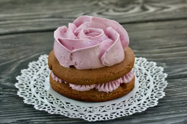 Çikolata hamuru ve yaban mersinli marşmelovdan yapılmış marshmallow sandviçleri. Bir gül şeklinde olsun. Dantel bir peçeteye, fırçalanmış çam ağacından tahtalara. Yakın çekim..