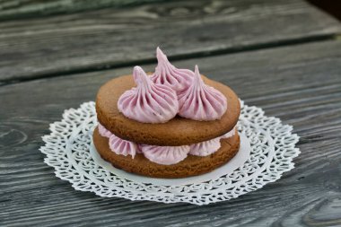 Çikolata hamuru ve yaban mersinli marşmelovdan yapılmış marshmallow sandviçleri. Dantel bir peçeteye, fırçalanmış çam ağacından tahtalara. Yakın çekim..