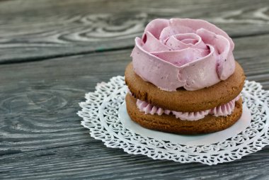 Çikolata hamuru ve yaban mersinli marşmelovdan yapılmış marshmallow sandviçleri. Bir gül şeklinde olsun. Dantel bir peçeteye, fırçalanmış çam ağacından tahtalara. Yakın çekim..