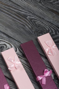 Hediyelerle dolu karton kutular. Pembe ve leylak, kurdele kurdelesiyle süslenmiş. Fırçalanmış çam ağaçlarının arka planında yatıyor..