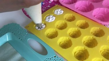 Marshmallow pişiriyorum. Hamur torbası ve başlık kullanan bir kadın silikon formunu şekerle dolduruyor..