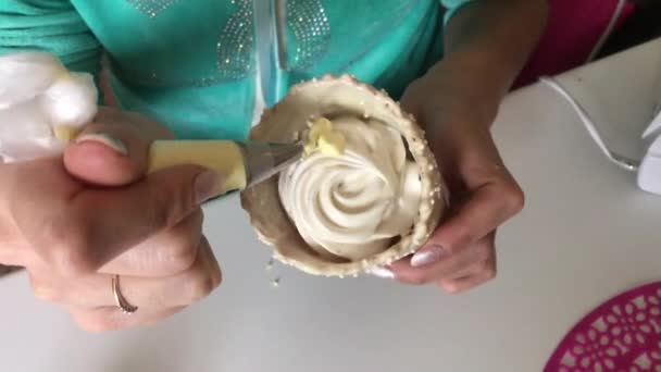 Una mujer está preparando malvaviscos en un cono de gofre. Usando una bolsa de pastelería y una boquilla, forma una masa. Disparo desde arriba. . — Vídeos de Stock