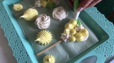 Elinde pasta torbası olan bir kadın şekerleme yapar. Farklı şekiller, renkler ve anlamlar. Bitmiş ürün bir tepside yatıyor..