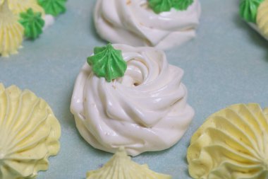 Yeşil yapraklarla süslenmiş beyaz ve sarı şekerlemeler. Yakın çekim..